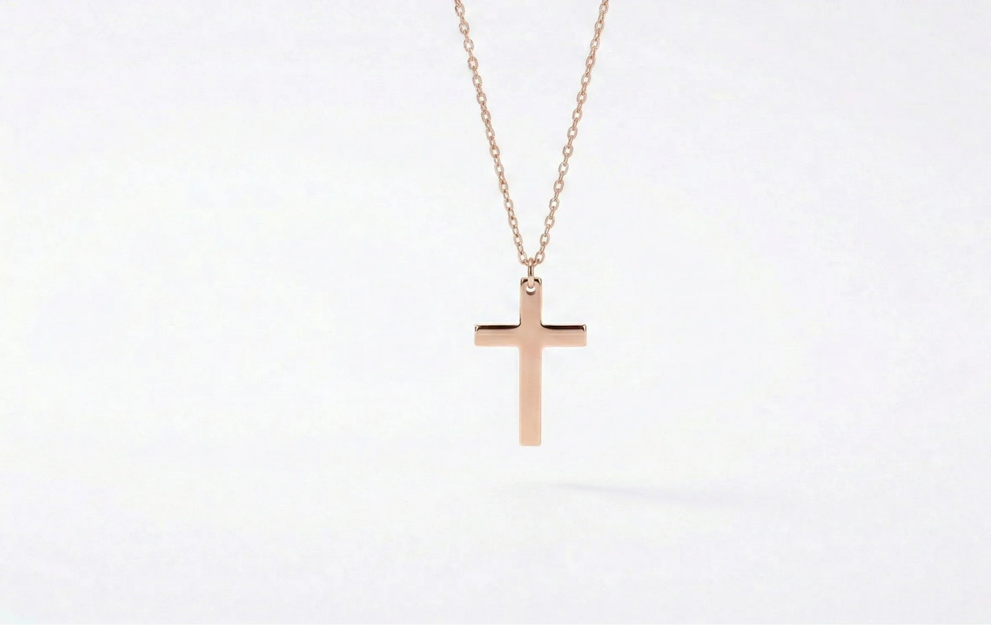 Rose gold cross necklace on a white background