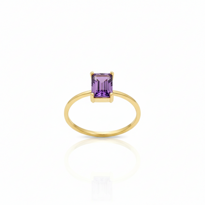 Gold ring with a purple gemstone on a white background