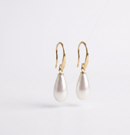 Pearl earrings with gold hooks on a light gray background
