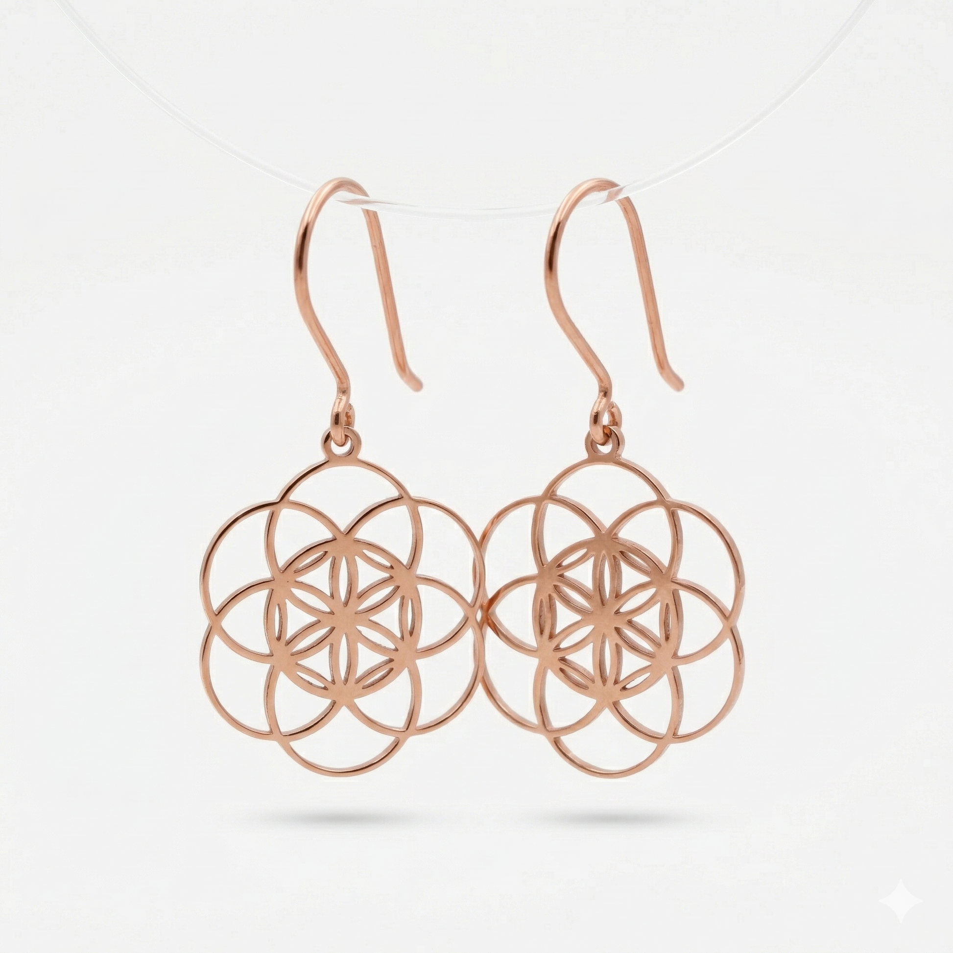 Rose gold earrings with intricate design on a light gray background