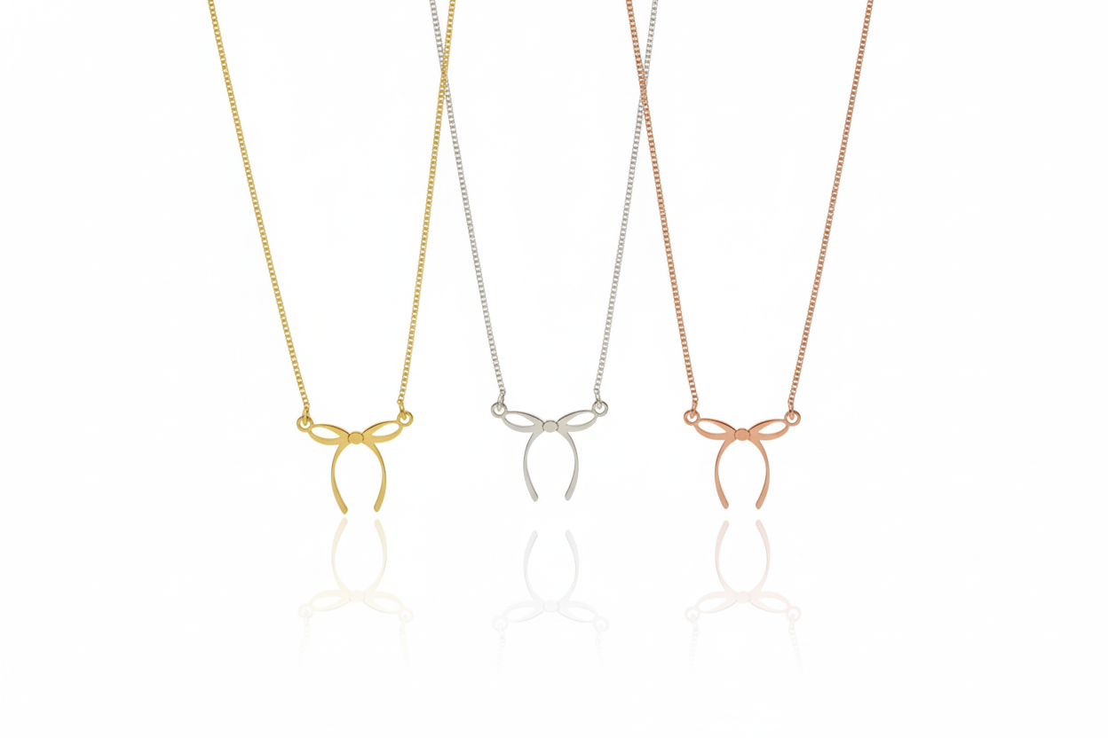 Three necklaces with bow pendants in gold, silver, and rose gold on a white background.