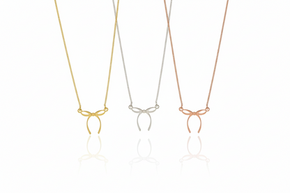 Three necklaces with bow pendants in gold, silver, and rose gold on a white background.