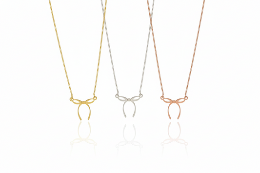 Three necklaces with bow pendants in gold, silver, and rose gold on a white background.
