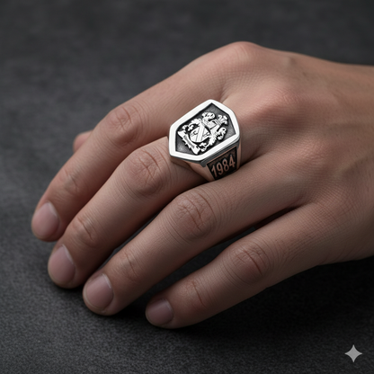 Silver ring with emblem and '1984' engraving on a hand against a dark background