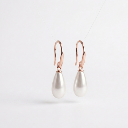 Pearl drop earrings with rose gold hooks on a light gray background