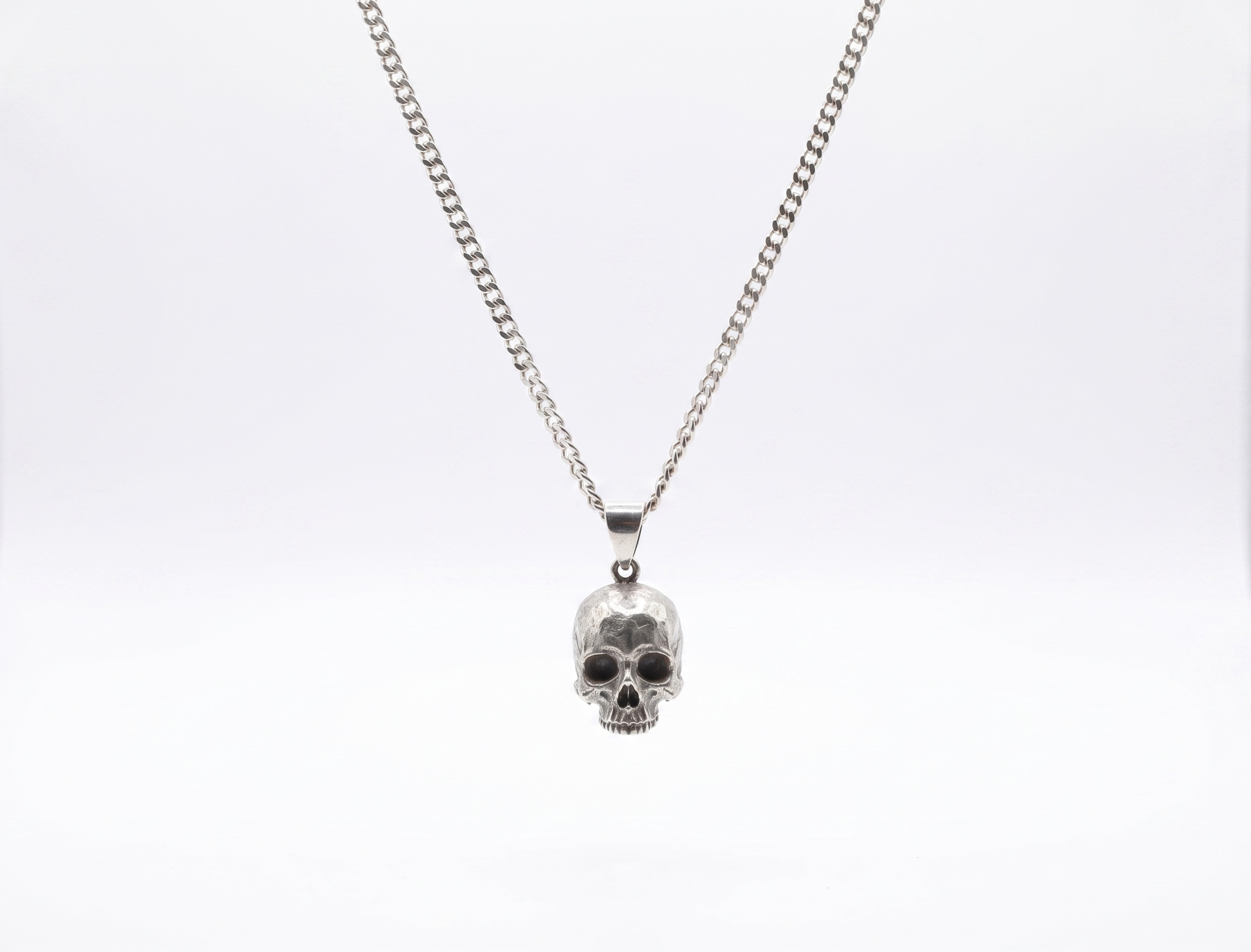 Silver skull pendant necklace on a white background