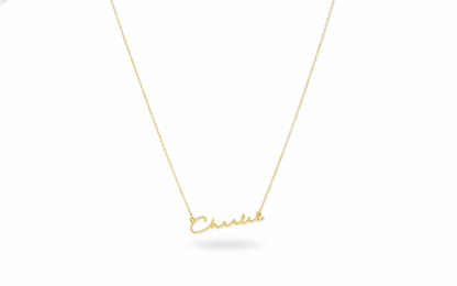 Gold necklace with 'Chanel' pendant on a white background