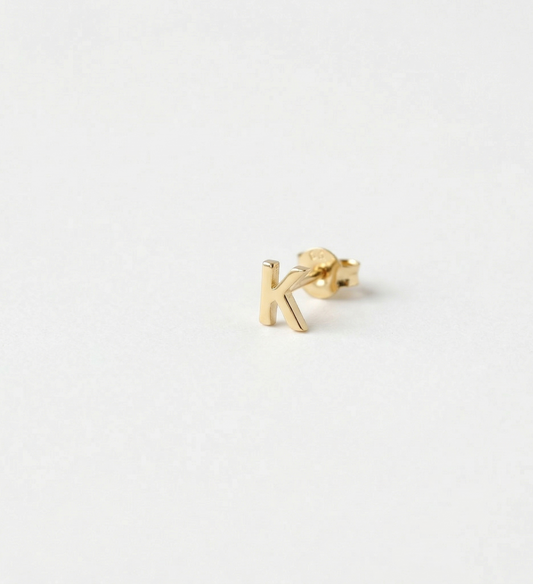 Gold letter 'k' earring on a white background