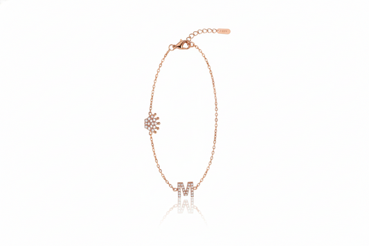 Rose gold bracelet with letter 'M' charm on a white background