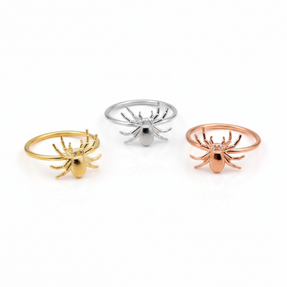 Three spider-shaped rings in gold, silver, and rose gold on a white background