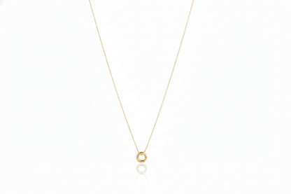 Gold necklace with a small round pendant on a white background