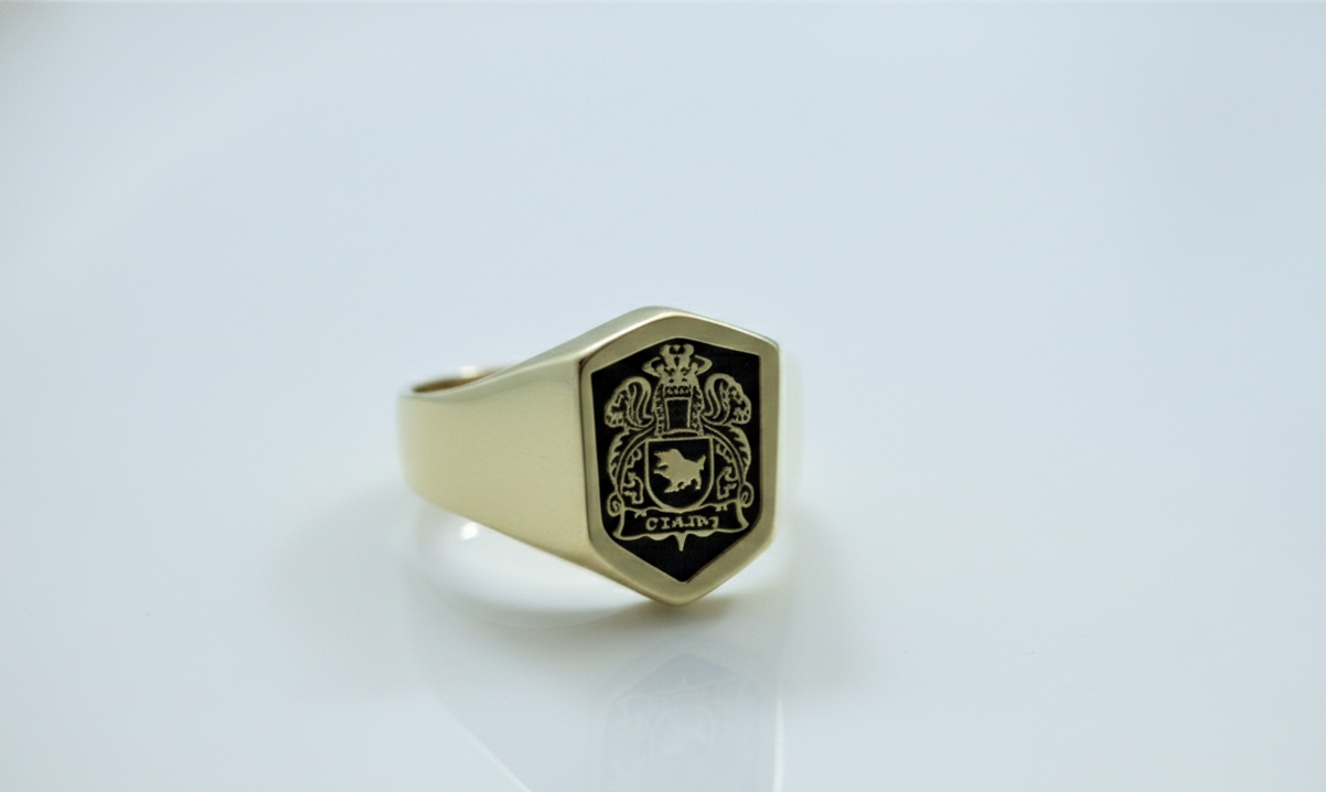 Gold ring with a black engraved design on a light gray background