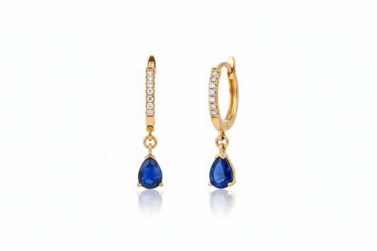 Gold earrings with blue gemstones on a white background