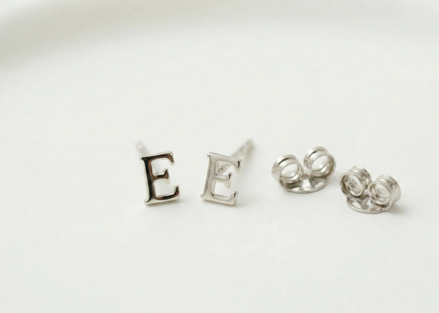 Silver letter 'E' earrings on a white background