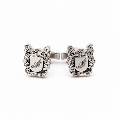 Silver cufflink with crest design on a white background
