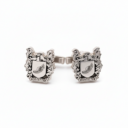 Silver cufflink with crest design on a white background