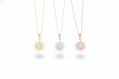 Three sun-shaped necklaces in gold, silver, and rose gold on a white background