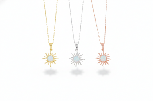 Three sun-shaped necklaces in gold, silver, and rose gold on a white background