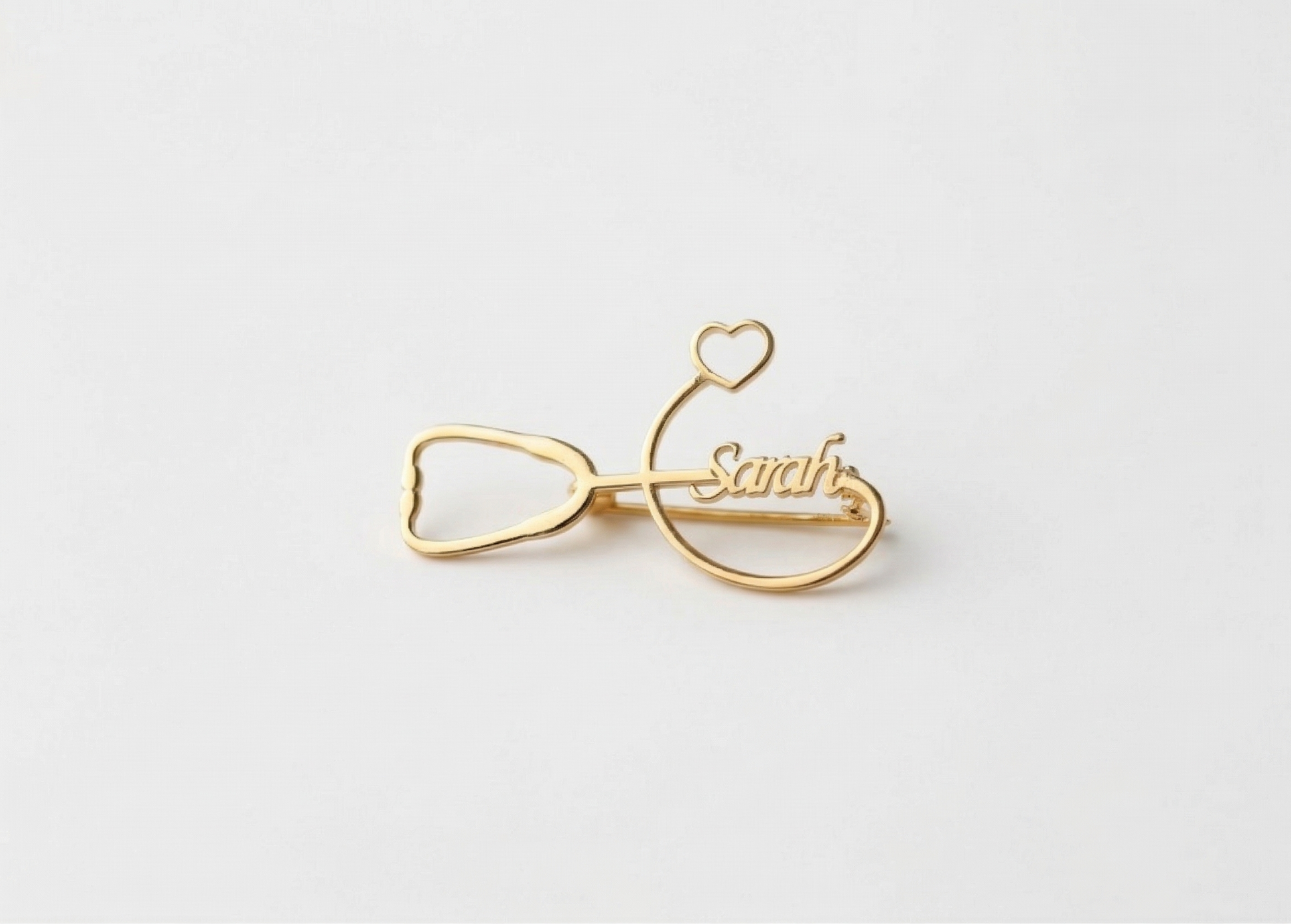 Gold bow-shaped hair clip with 'Sarah' engraved on a white background