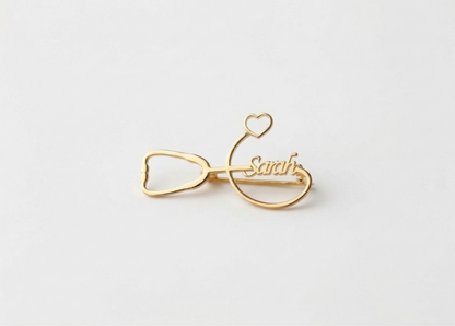 Gold bow-shaped hair clip with 'Sarah' engraved on a white background