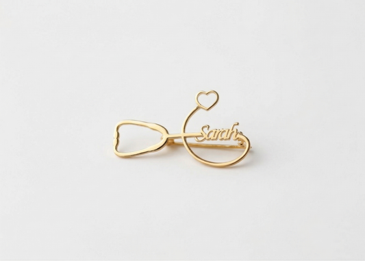 Gold bow-shaped hair clip with 'Sarah' engraved on a white background