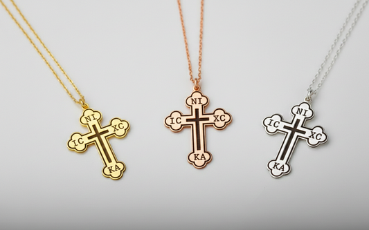 Three cross-shaped pendants on necklaces against a light gray background