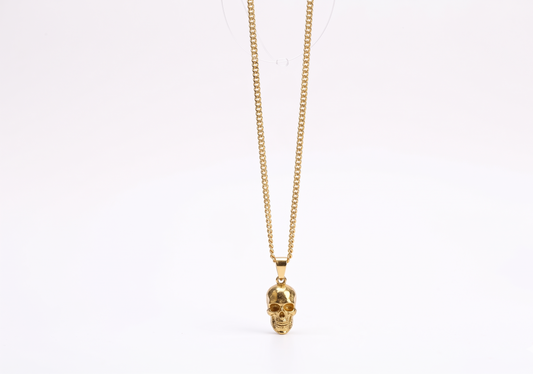 Gold skull pendant necklace on a white background