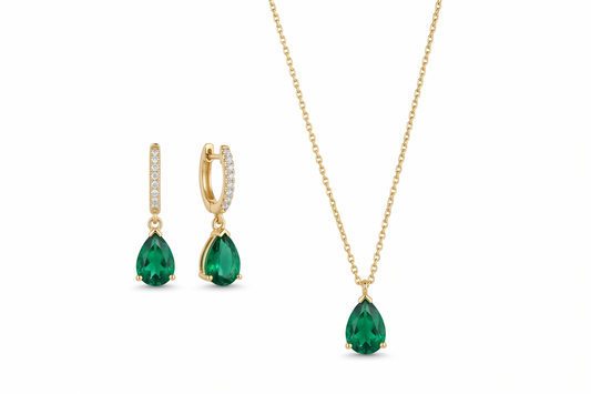 Gold jewelry set with green gemstones on a white background
