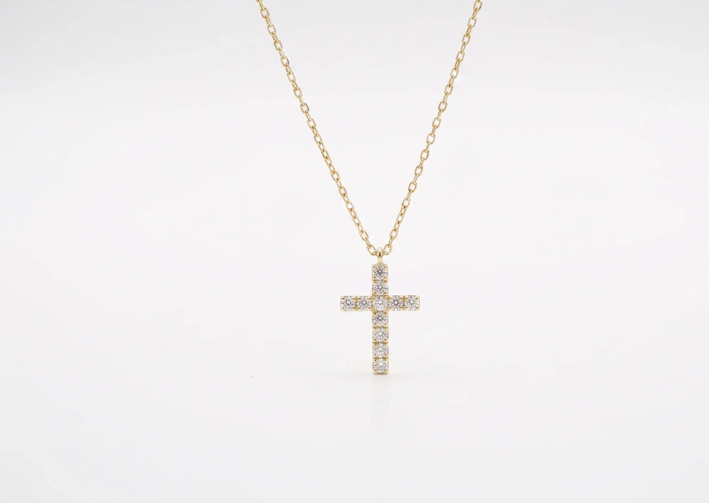 Gold cross necklace with diamonds on a white background