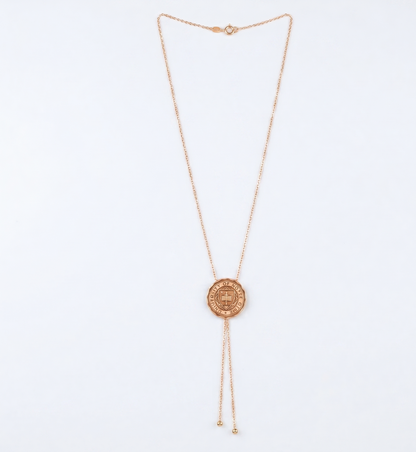 Rose gold necklace with a circular university logo pendant on a light blue background