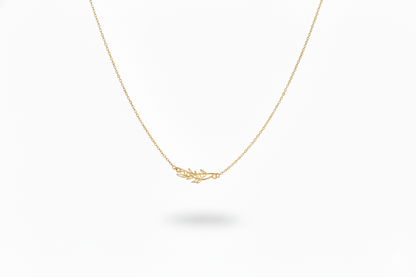 Gold necklace with a delicate leaf pendant on a white background