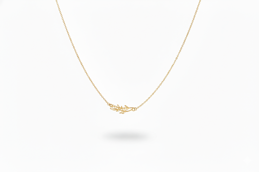 Gold necklace with a delicate leaf pendant on a white background