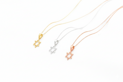 Three necklaces with star-shaped pendants in gold, silver, and rose gold on a white background.