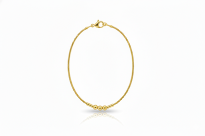 Gold bracelet with three beads on a white background