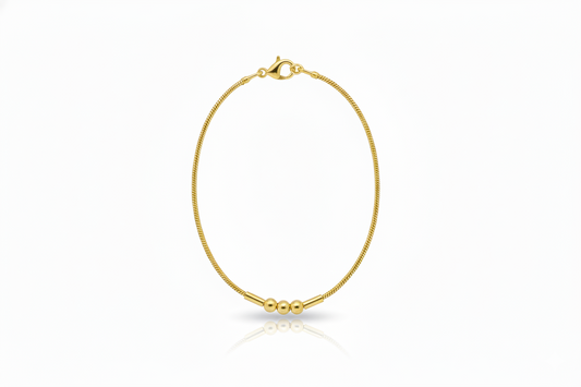 Gold bracelet with three beads on a white background