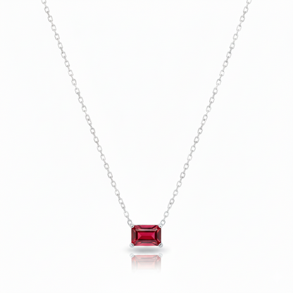 Silver necklace with a red gemstone pendant on a white background