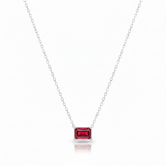 Silver necklace with a red gemstone pendant on a white background