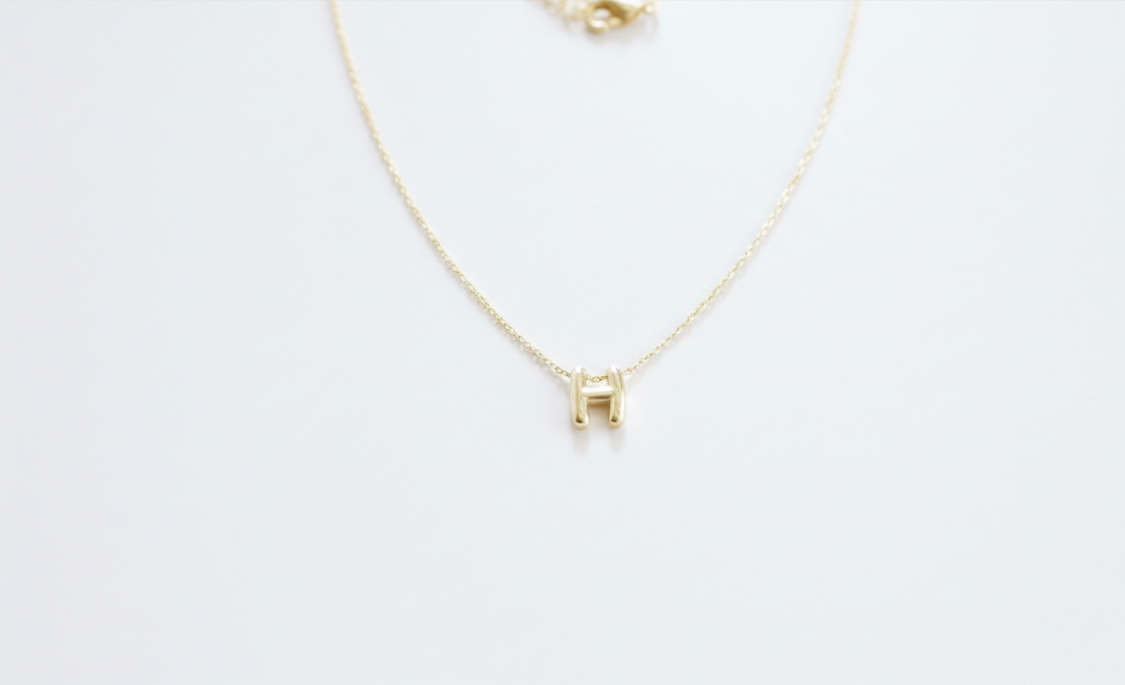 Gold necklace with a small square pendant on a white background