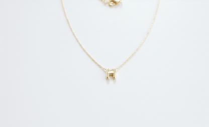 Gold necklace with a small square pendant on a white background