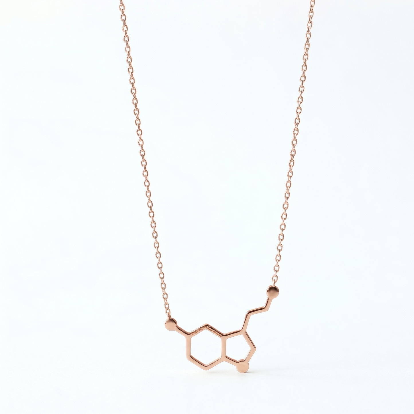 Rose gold molecular pendant necklace on a white background