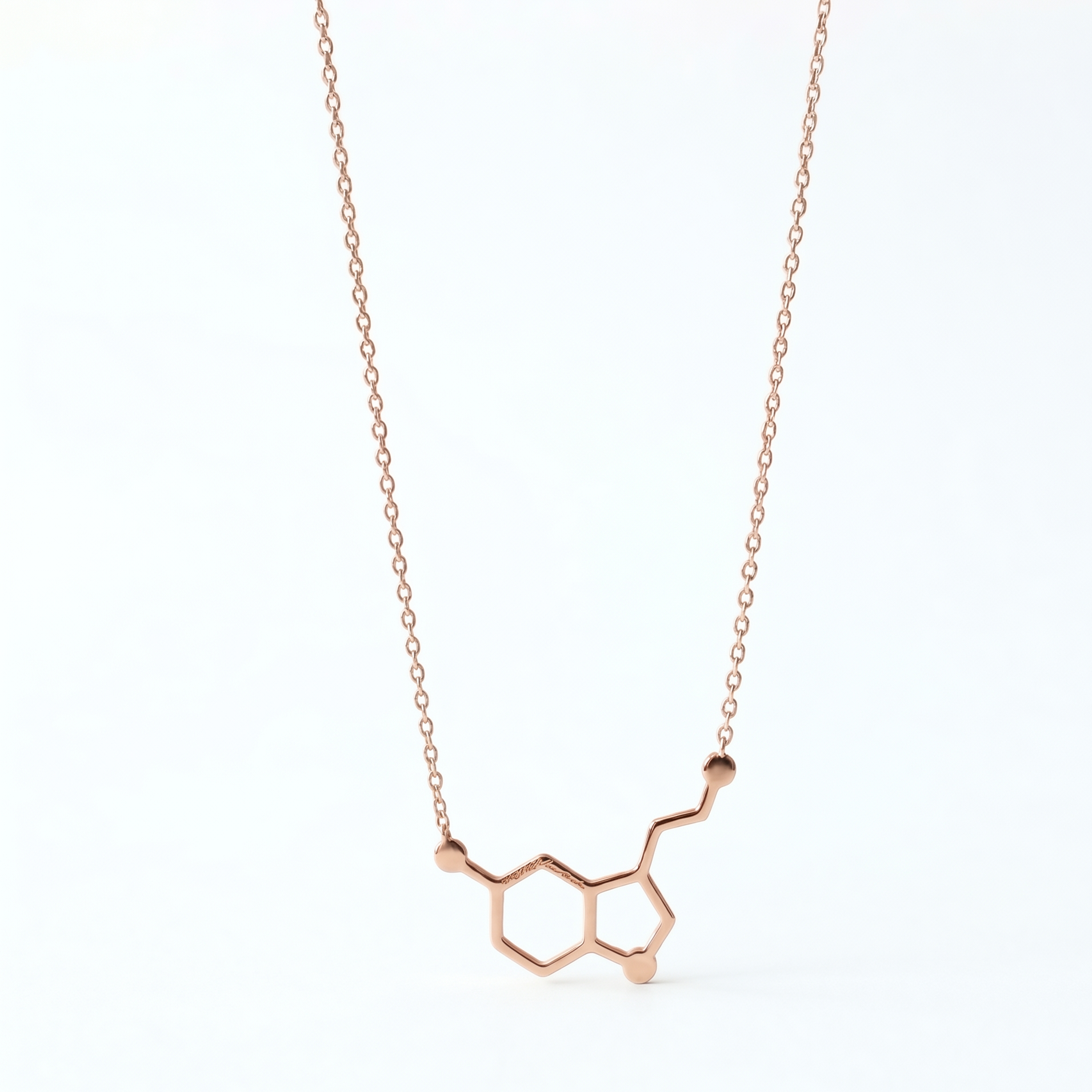 Rose gold molecular pendant necklace on a white background