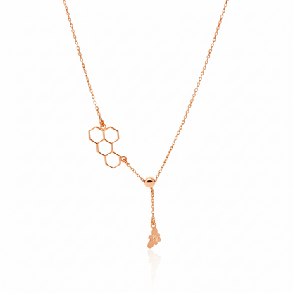 Rose gold necklace with geometric pendant on a white background