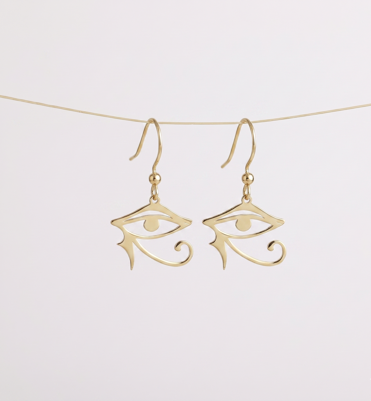 Gold eye-shaped earrings on a white background