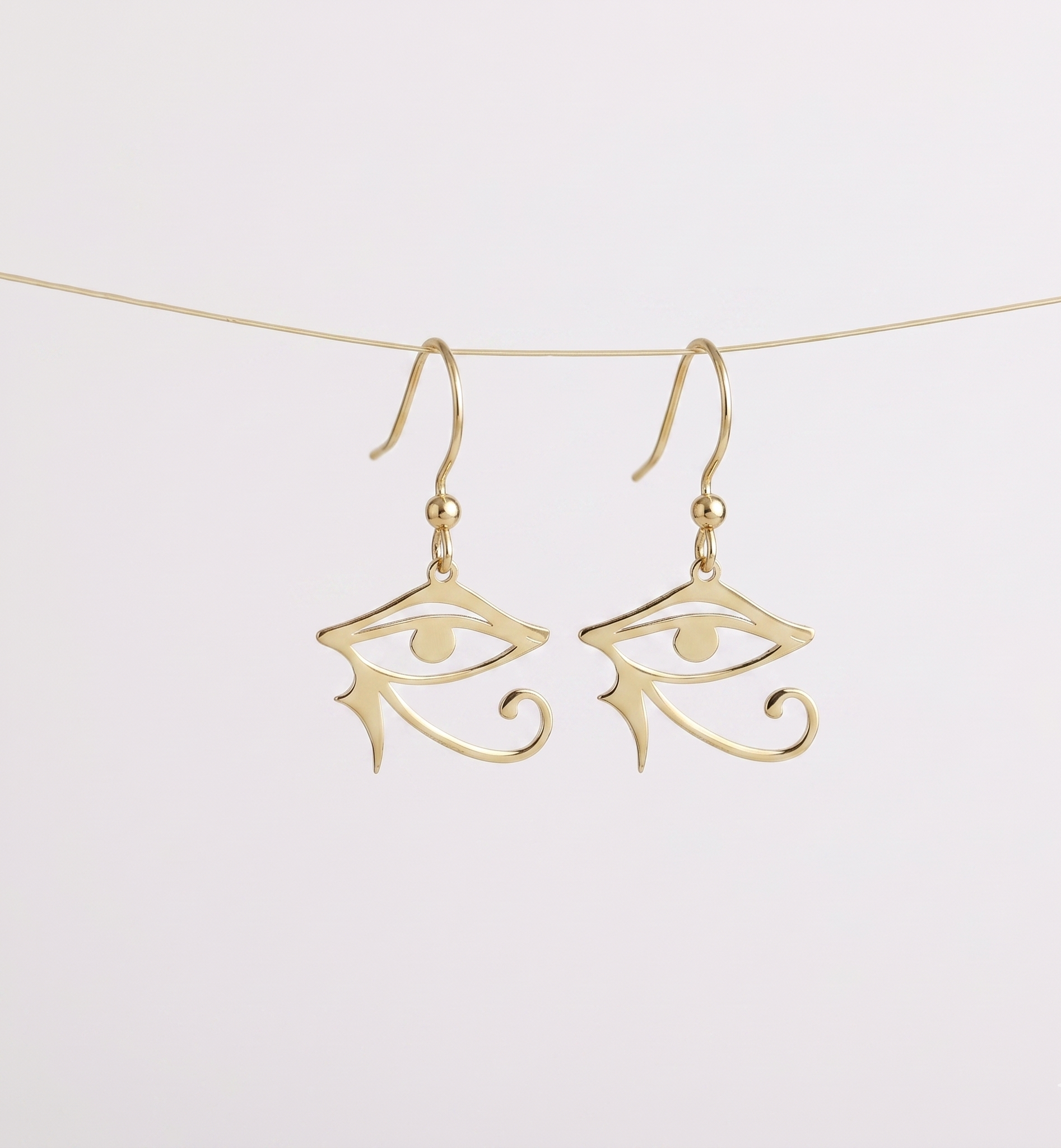 Gold eye-shaped earrings on a white background
