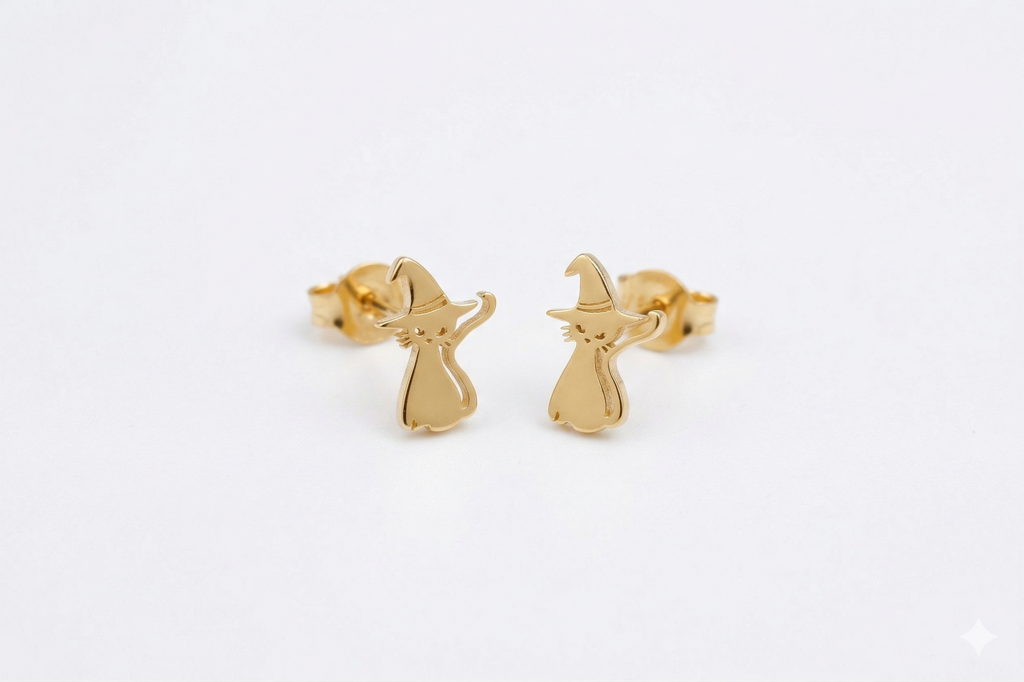 Gold witch earrings on a light gray background