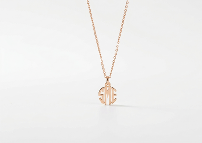 Rose gold necklace with a monogram pendant on a light gray background