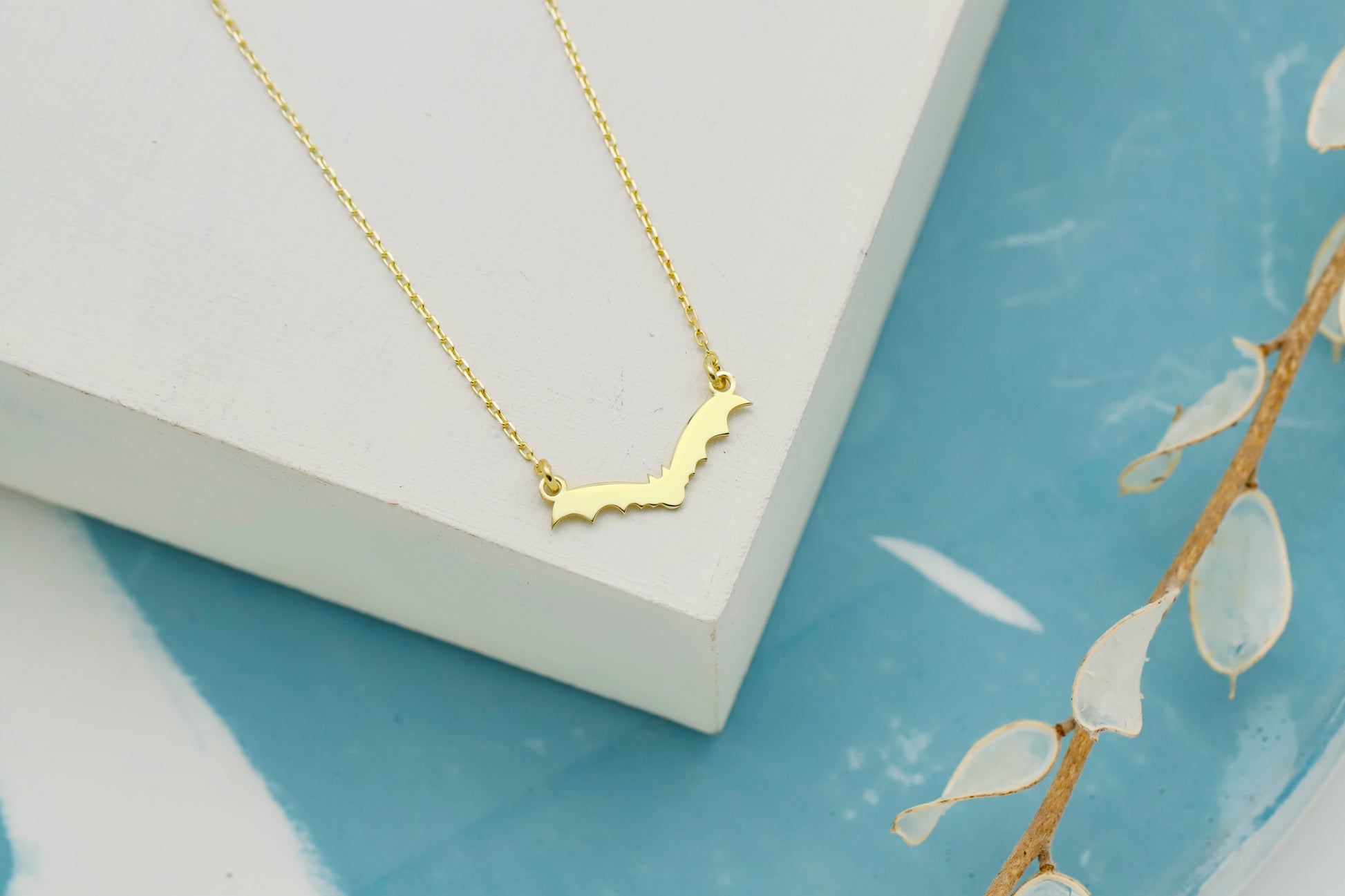 Gold necklace on a white surface with a blue background