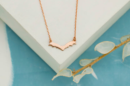 Rose gold necklace on a white stand with a light blue background