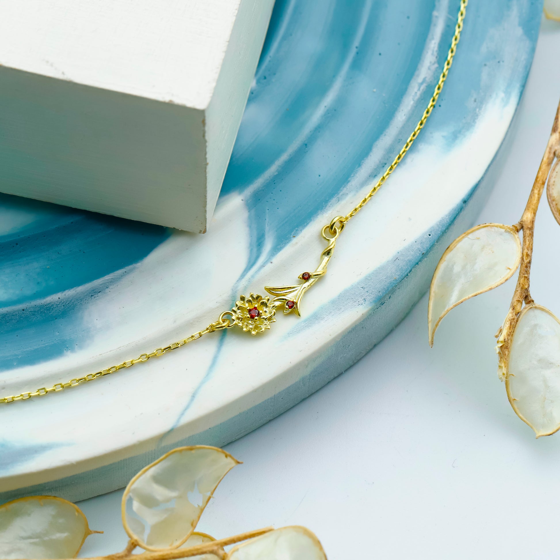 Gold necklace with floral pendant on a decorative plate