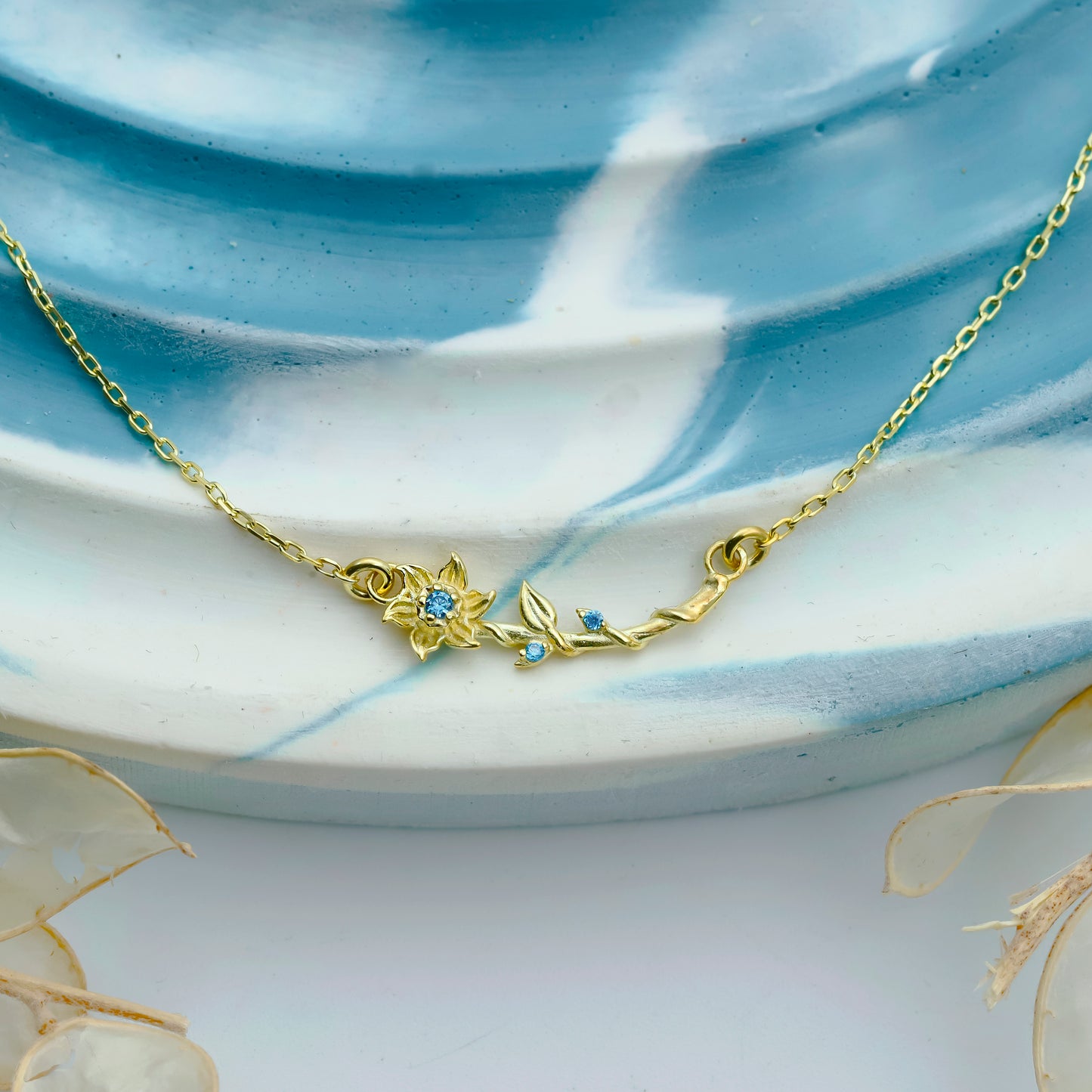 Gold necklace with floral design on a ceramic plate